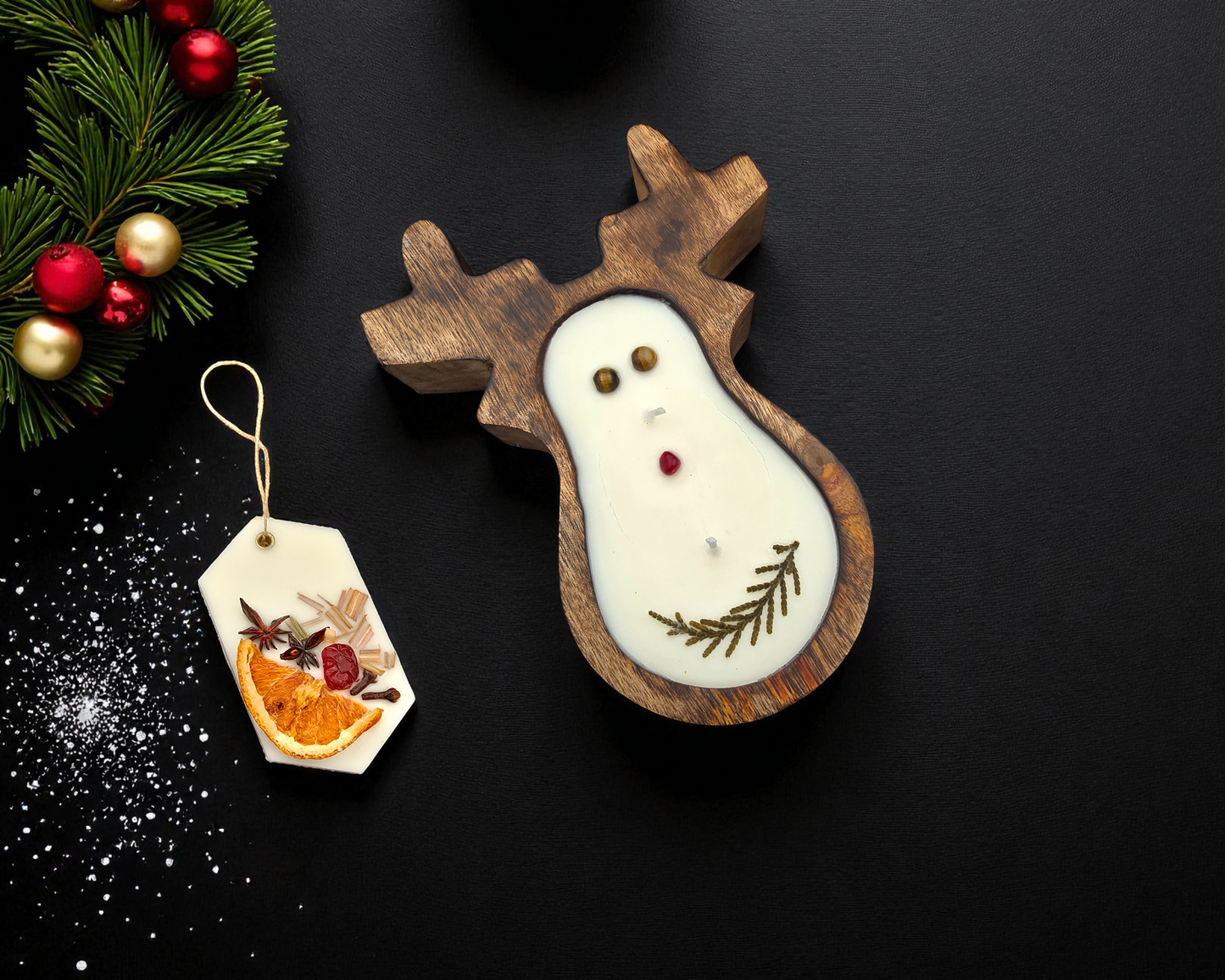 Wooden reindeer decoration with a candle on a black background, accompanied by a small tag with an orange and berry design.