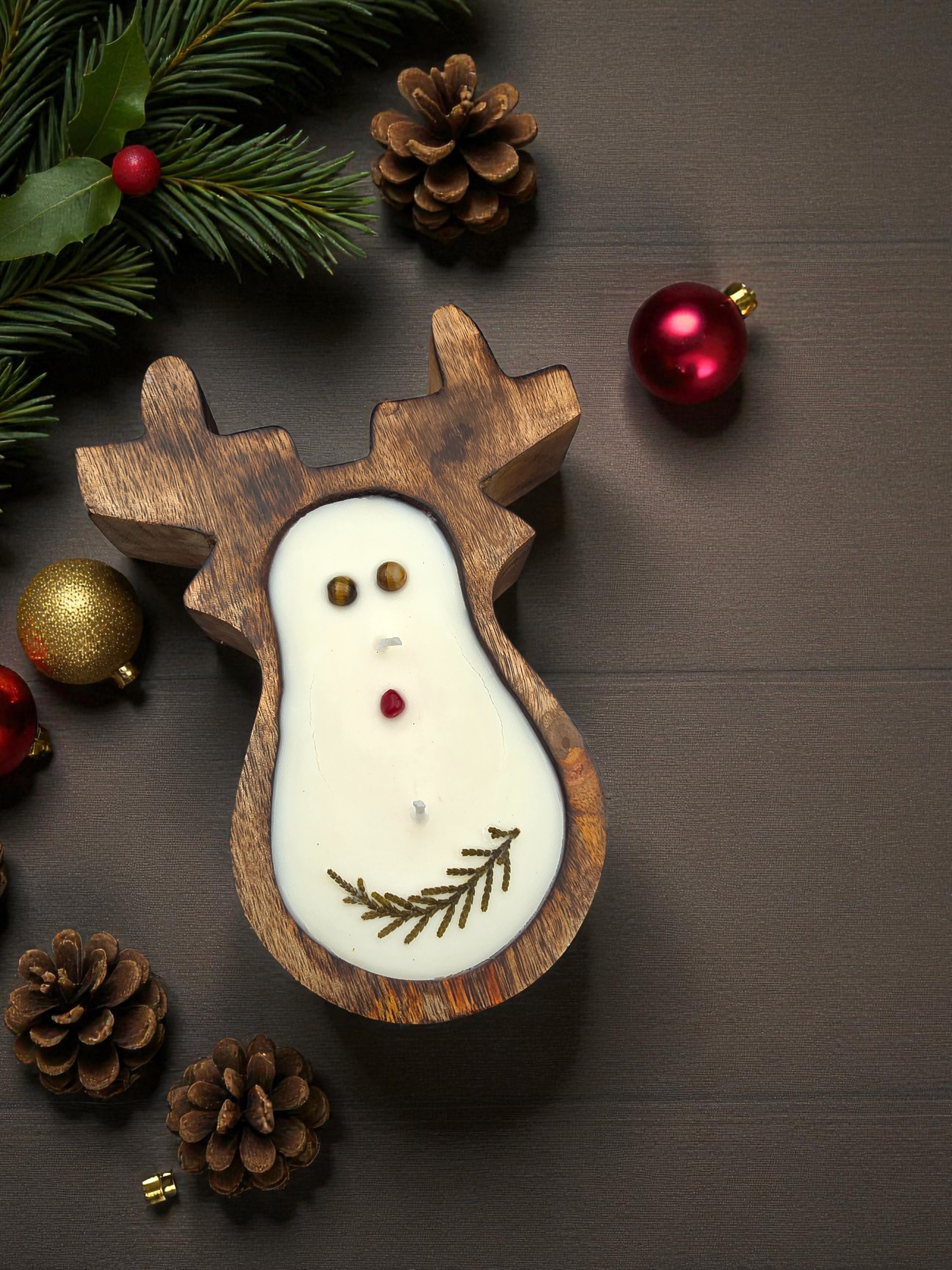 Wooden reindeer-shaped candle with Christmas decorations on a wooden surface