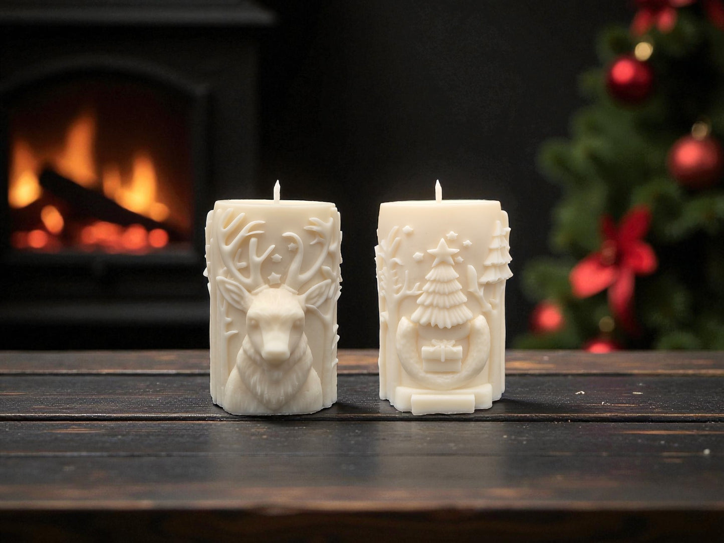 Two decorative candles with animal and tree designs on a wooden table with a fireplace and Christmas tree in the background.