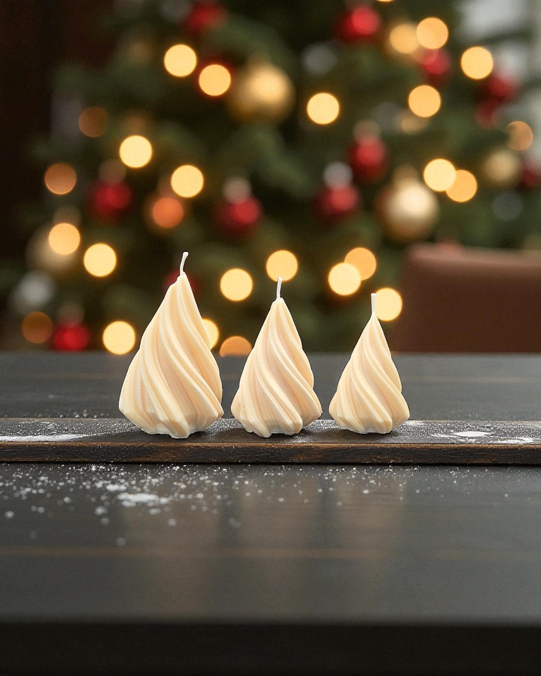 Three white candles on a wooden surface with a blurred Christmas tree in the background
