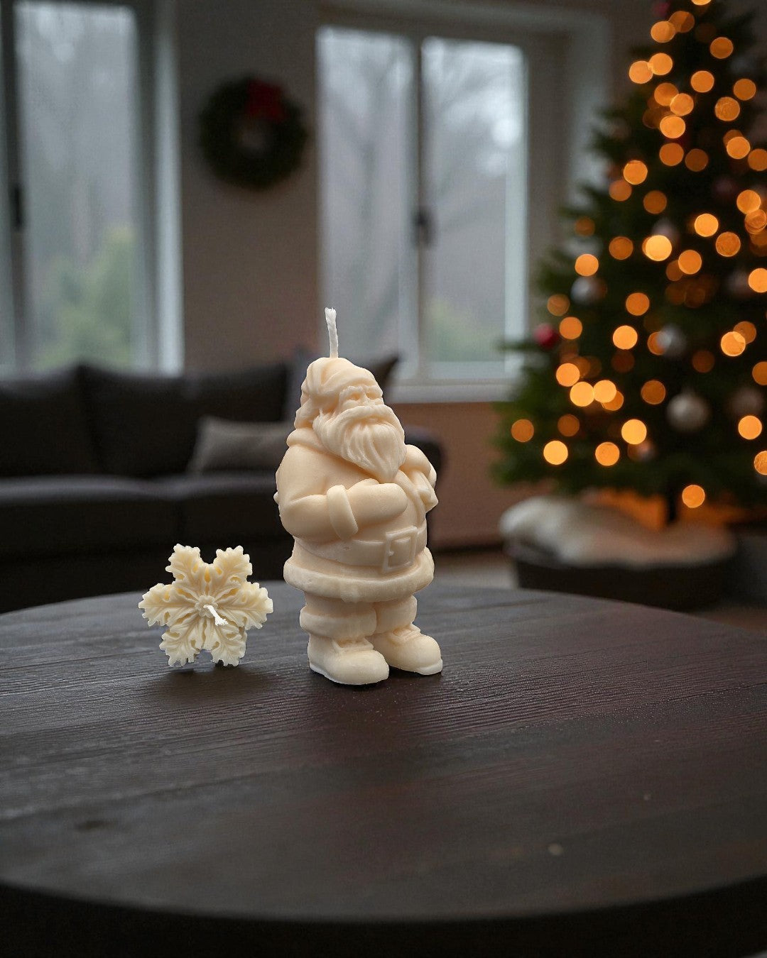 Santa Claus candle and flower-shaped candle on a table with a Christmas tree in the background