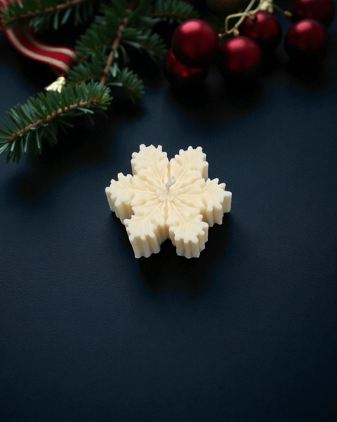Snowflake-shaped white soap on a dark surface with Christmas decorations.